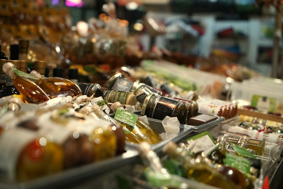 Premium pantry items including olive oil, jars, and grocery staples displayed at a market.